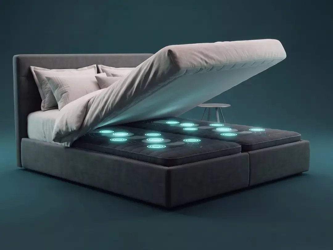 Ein Boxspringbett mit angehobener Matratze, darunter zwei ANDUFIT-Module mit leuchtenden Massagezonen